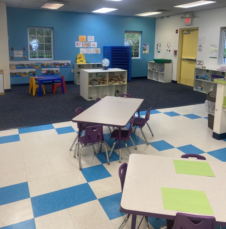 Classroom with small tables and chairs, blue walls, and checkered floor