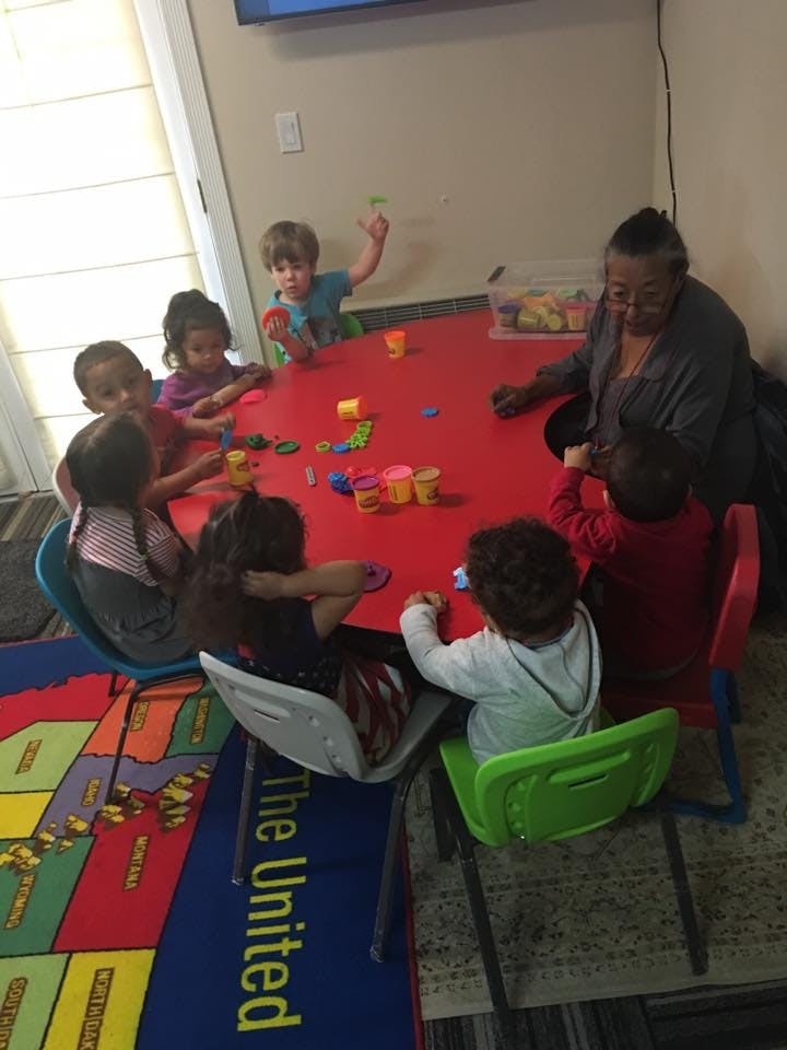 Adult and children playing with toys at a red table