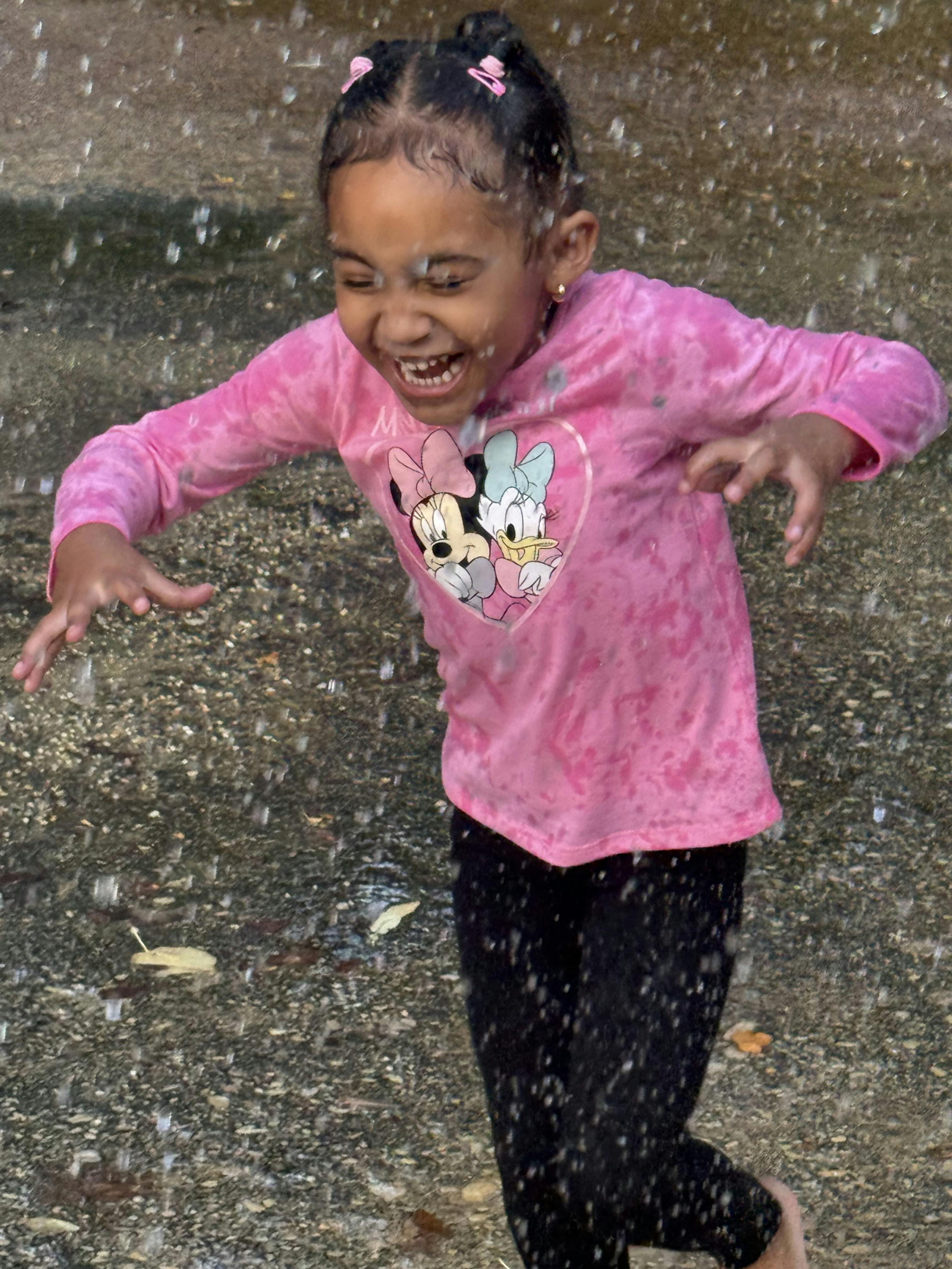 Child in a pink Minnie Mouse shirt playing in water