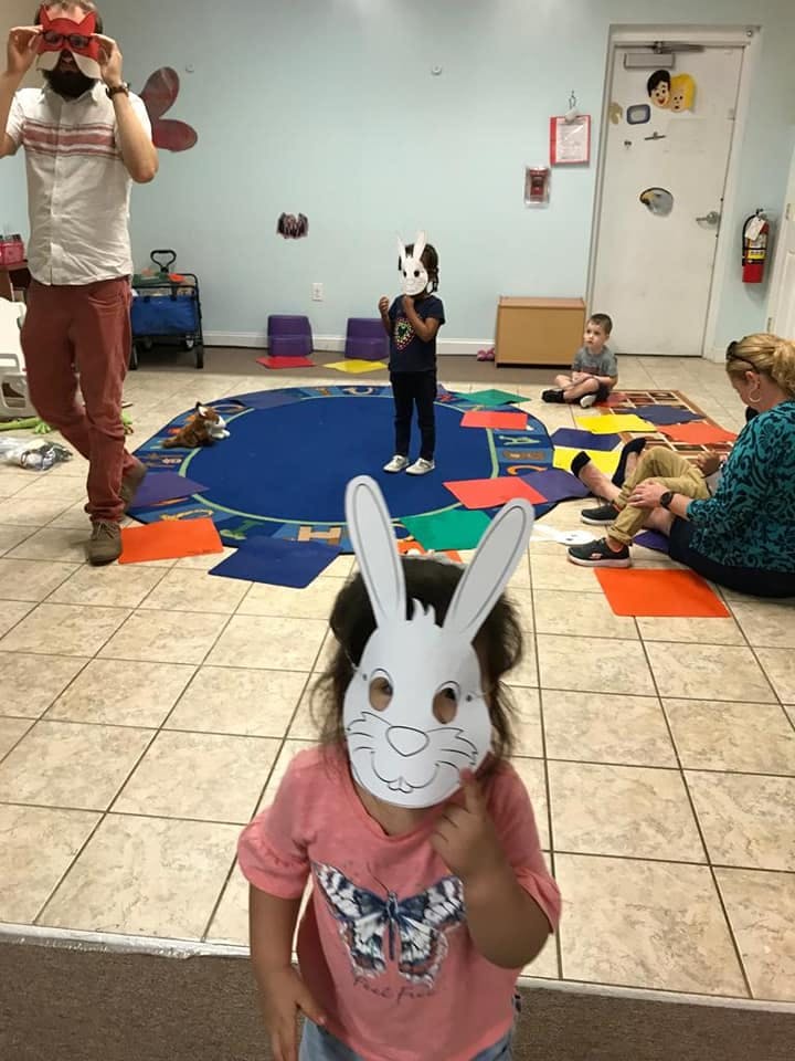 Child wearing a bunny mask in a room with other people