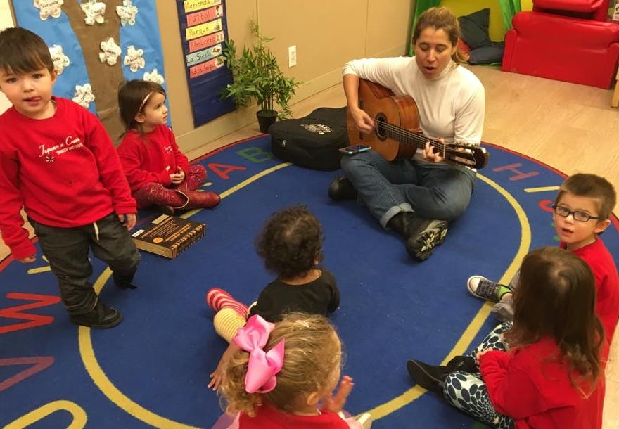 Adult playing guitar for children in a classroom