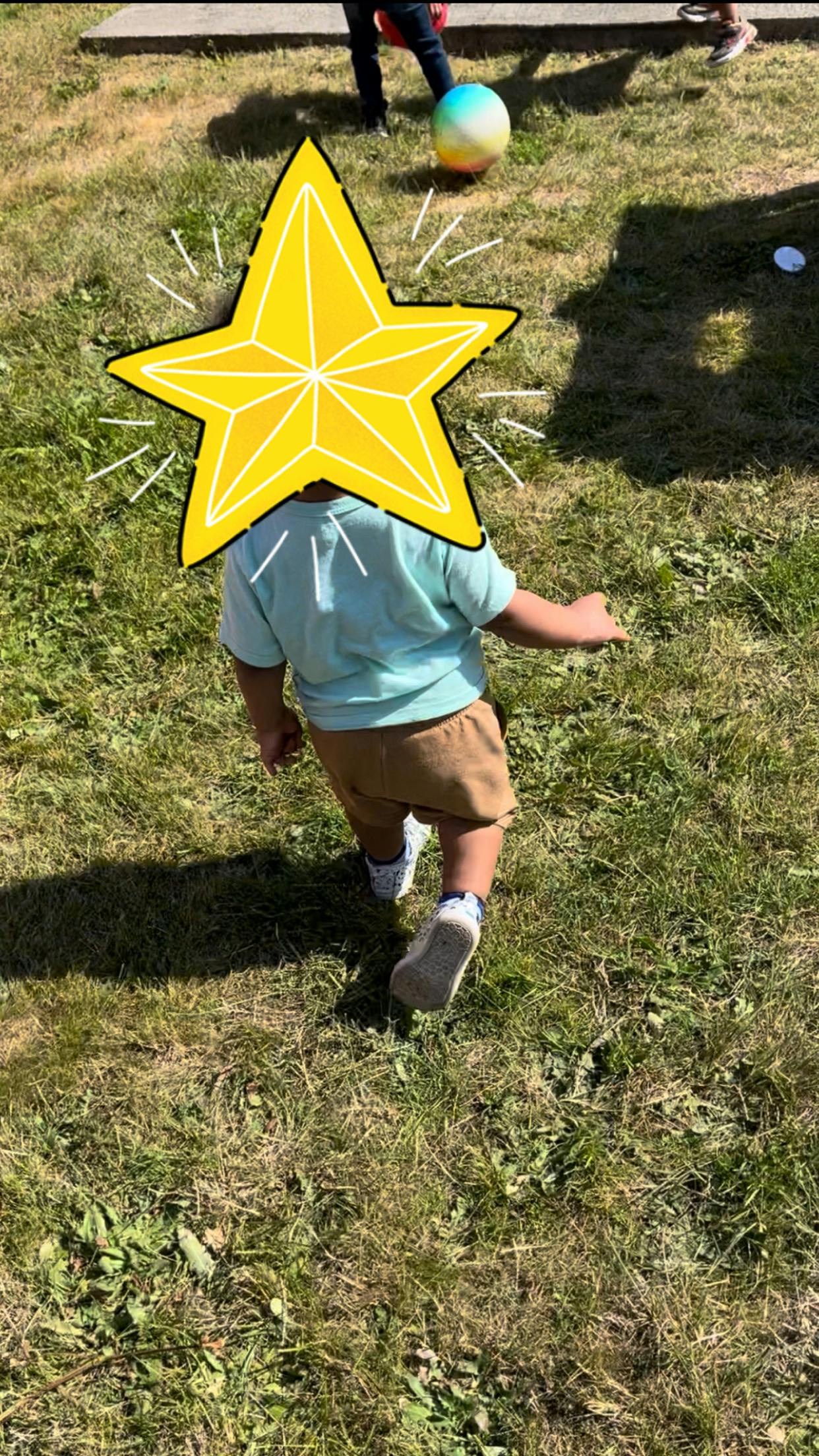 Child walking on grass with a star covering their head