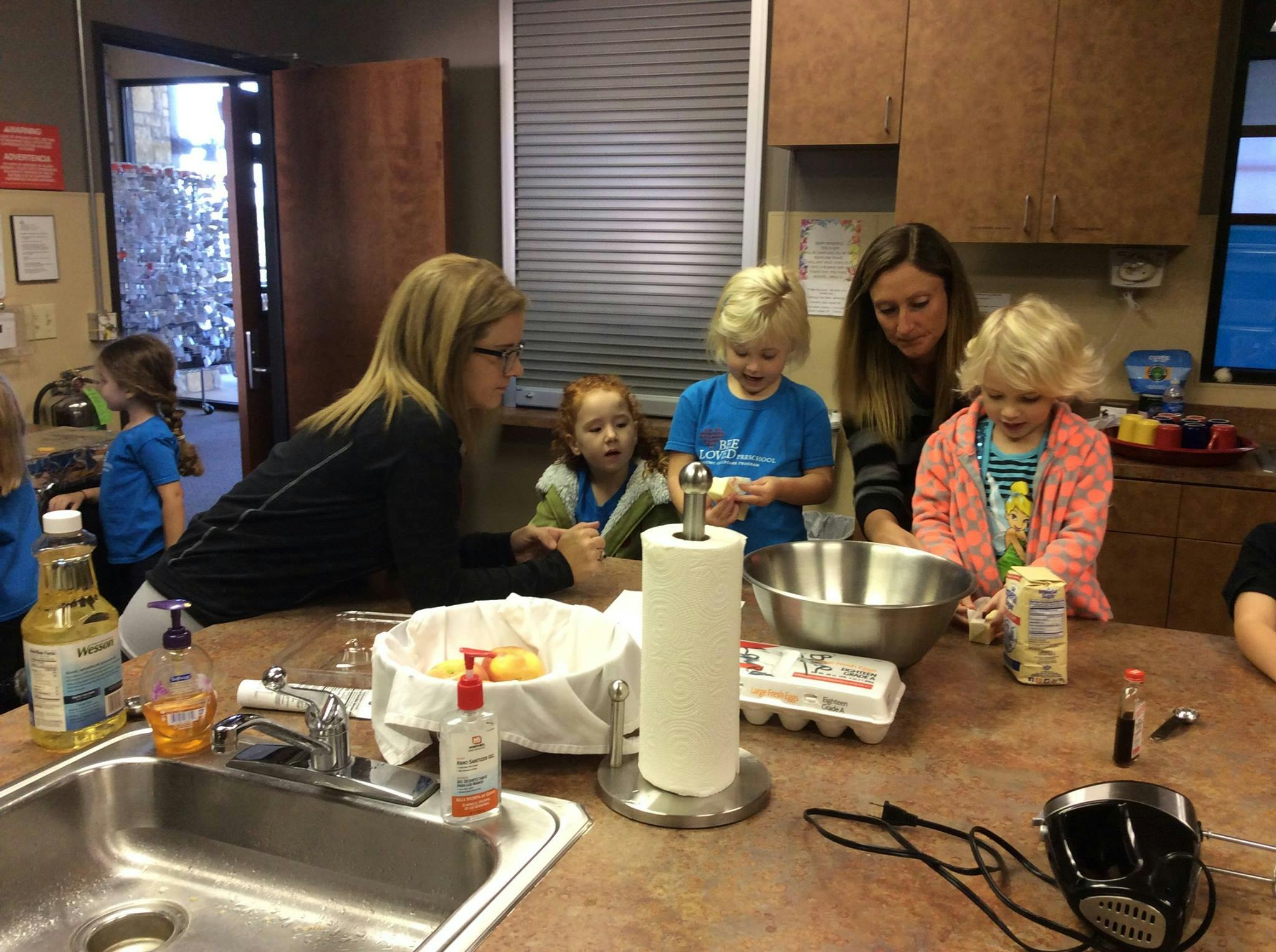 Adults and children gathered around a kitchen counter with baking ingredients