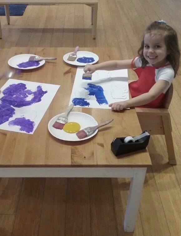 Child painting with blue paint at a table