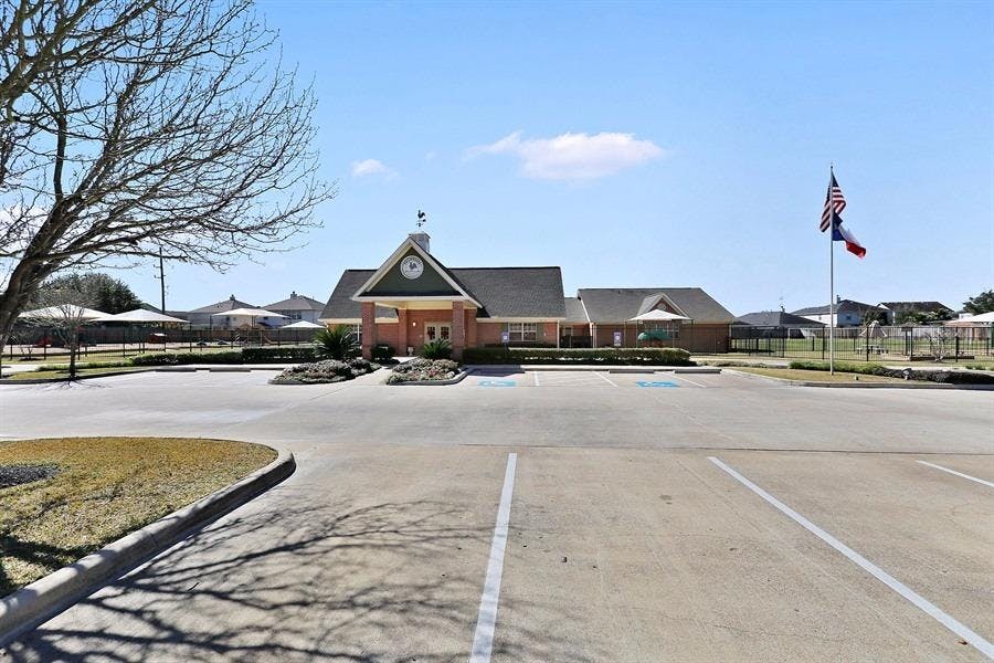 Building with a clock tower and a flag pole in a parking lot