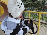 Child in a cat hat playing with a toy steering wheel