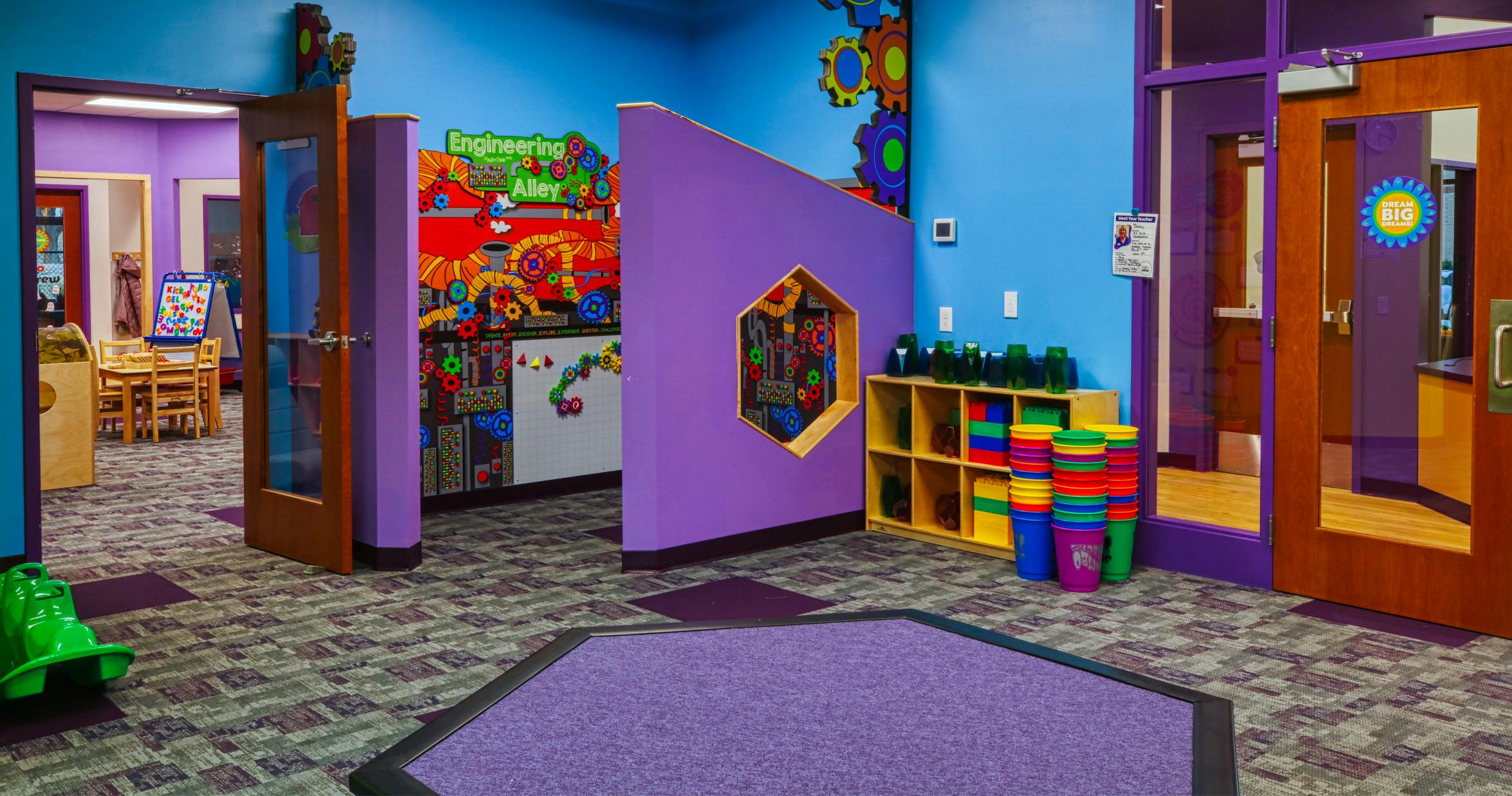 Children's play area with colorful walls, large gears, and "Engineering Alley" sign