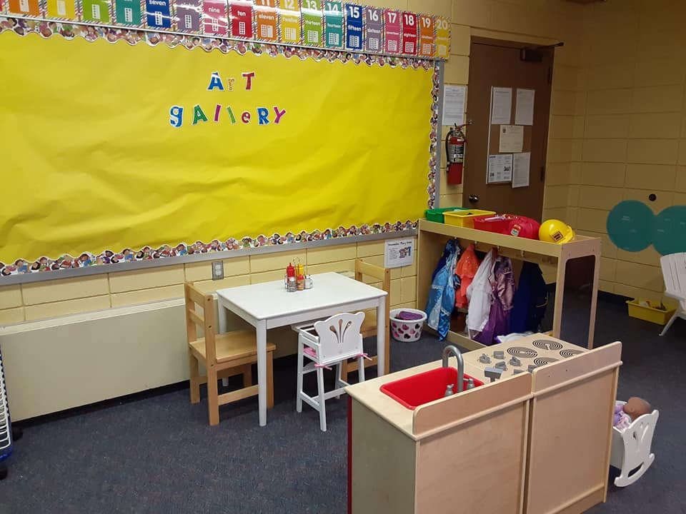 Classroom with small table and chairs, play kitchen, and dress-up clothes