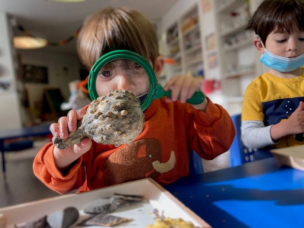 Child looking through a magnifying glass at a textured object