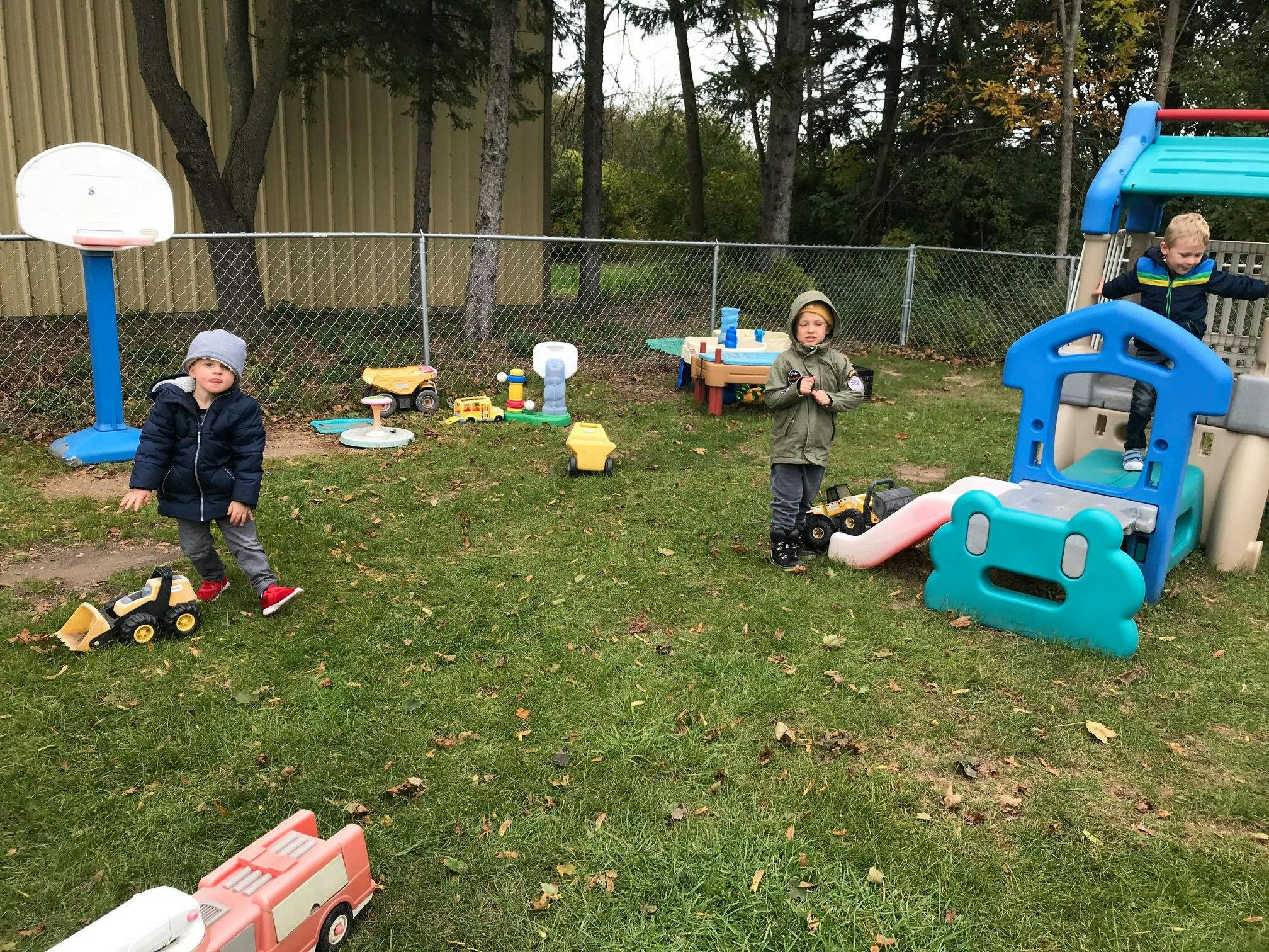 Children playing with toys in a grassy outdoor area