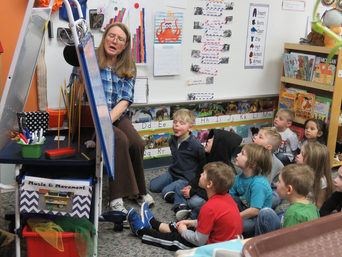 Adult person teaching a group of children in a classroom