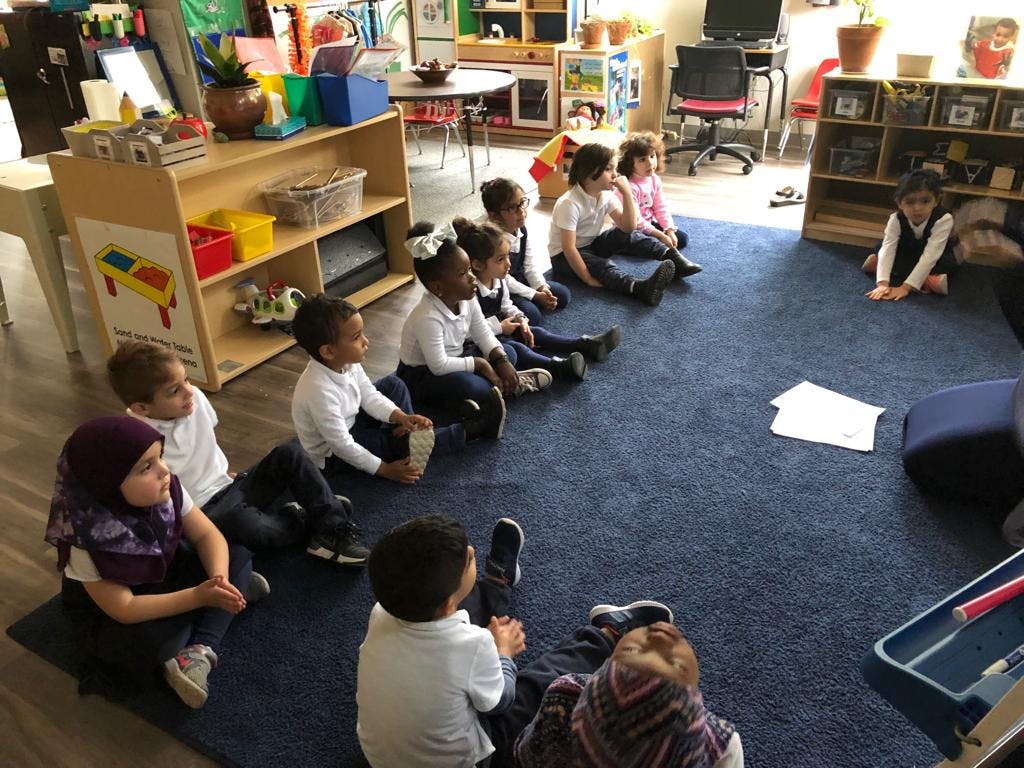 Children sitting on a blue rug in a classroom