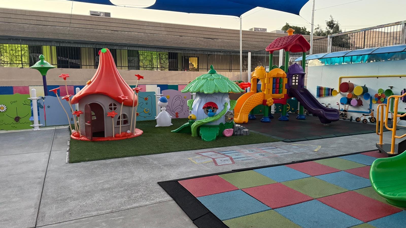 Colorful playground with small playhouses, slides, and outdoor sensory panels