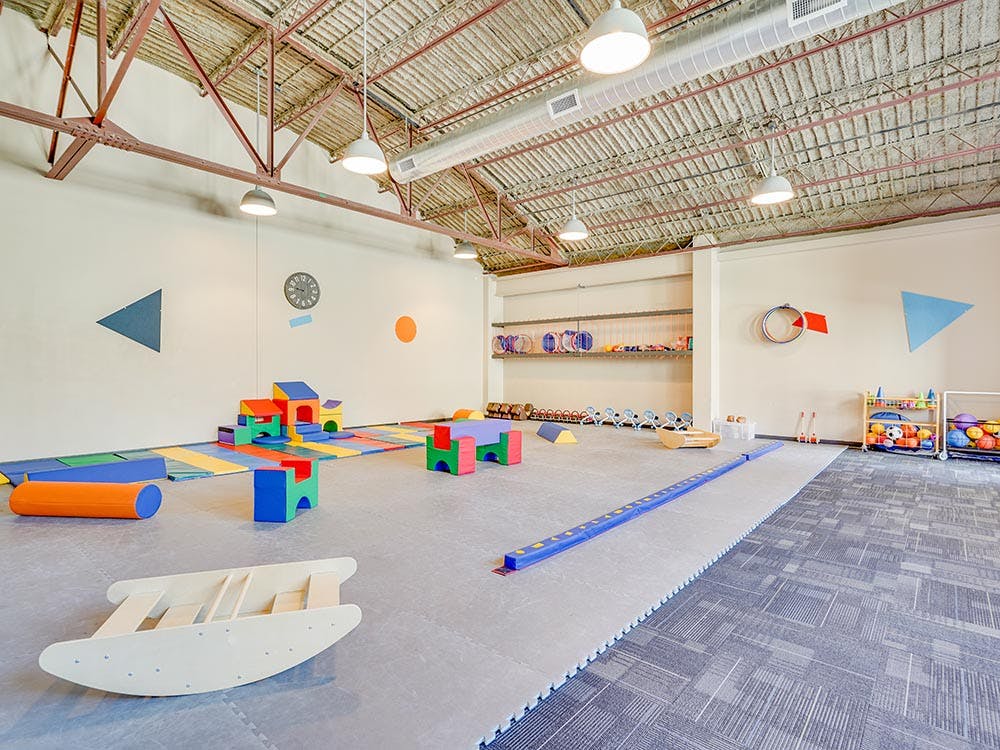 Children's play area with soft blocks, colorful mats, and a balance beam