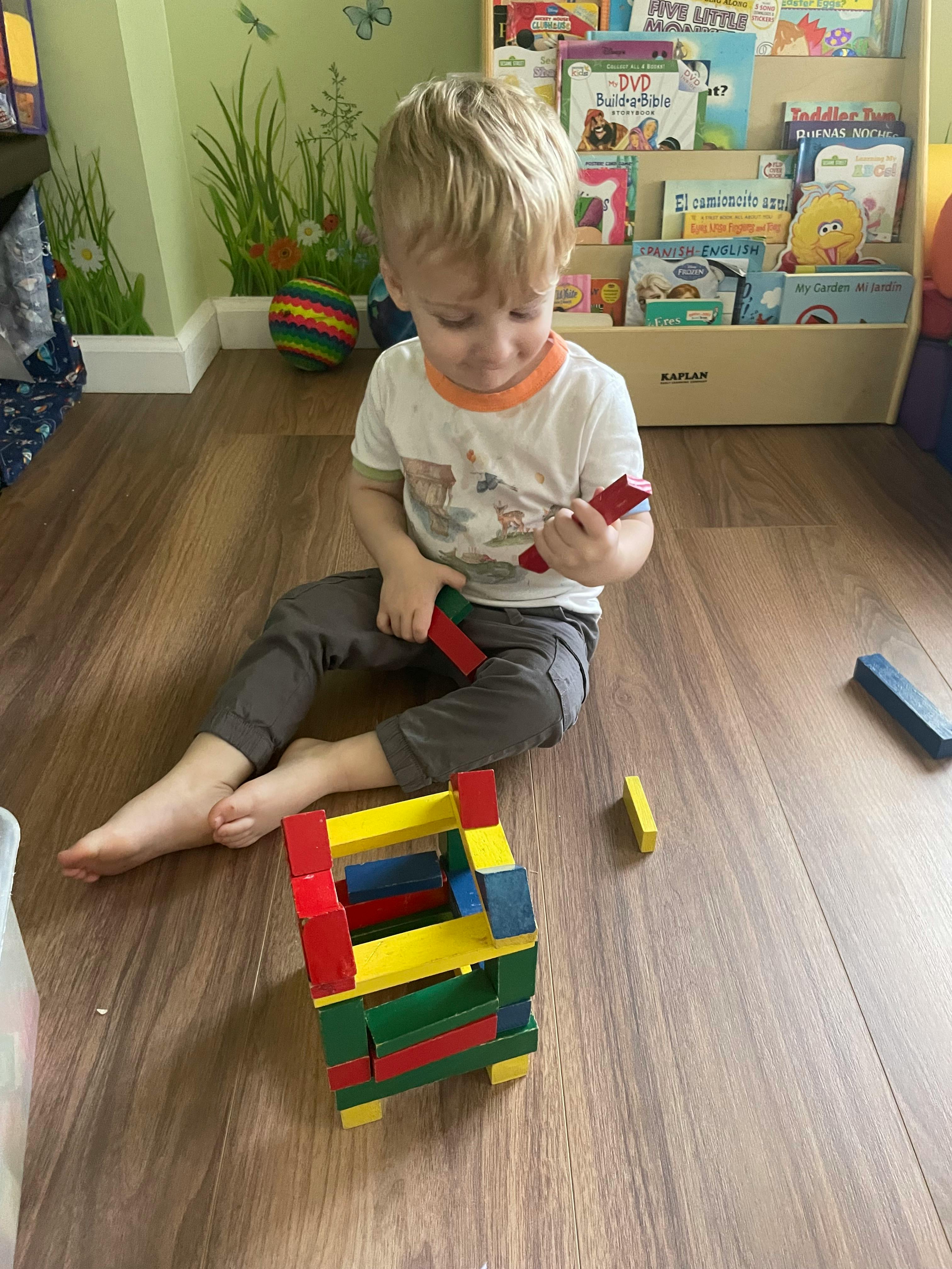 Child sitting on floor playing with colorful building blocks