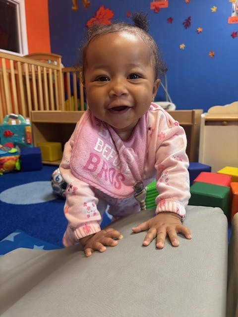 A happy child crawling on soft foam shapes in a playroom