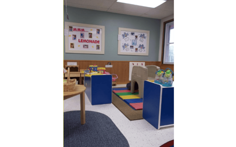 Classroom with child-sized tables, chairs, and play equipment, with a window
