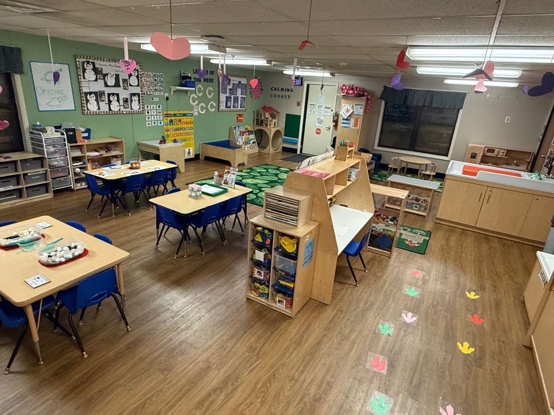 Empty classroom with small tables and chairs, and play areas