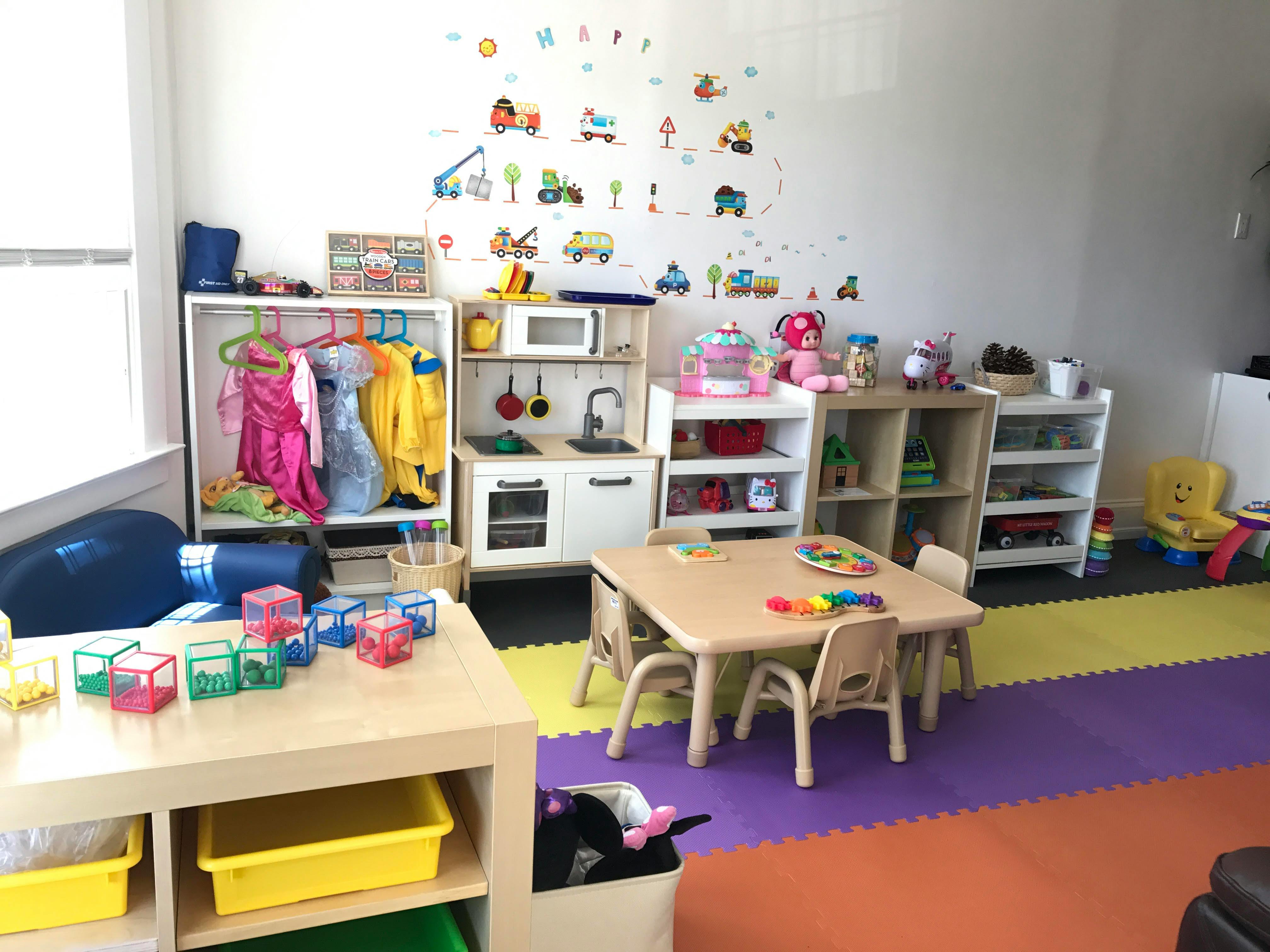 Playroom with small tables and chairs, toy kitchen, and dress-up clothes