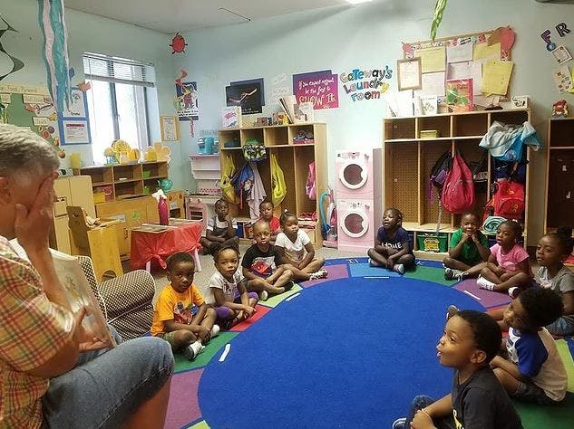 Adult reading to children sitting on a rug in a classroom