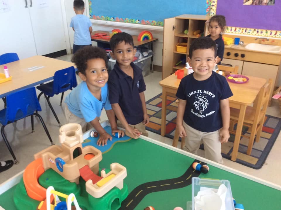 Three children playing with toys in a classroom
