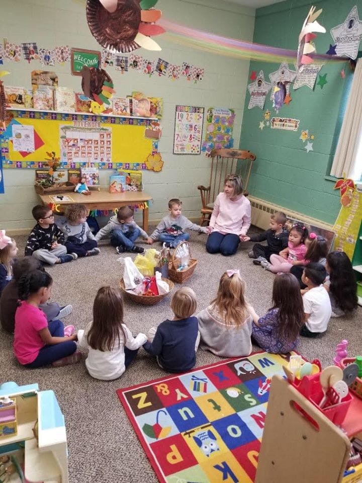 Adult and children sitting in a circle on the floor in a classroom