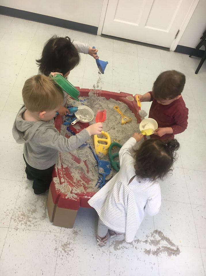 Four children playing in a sand table with toys