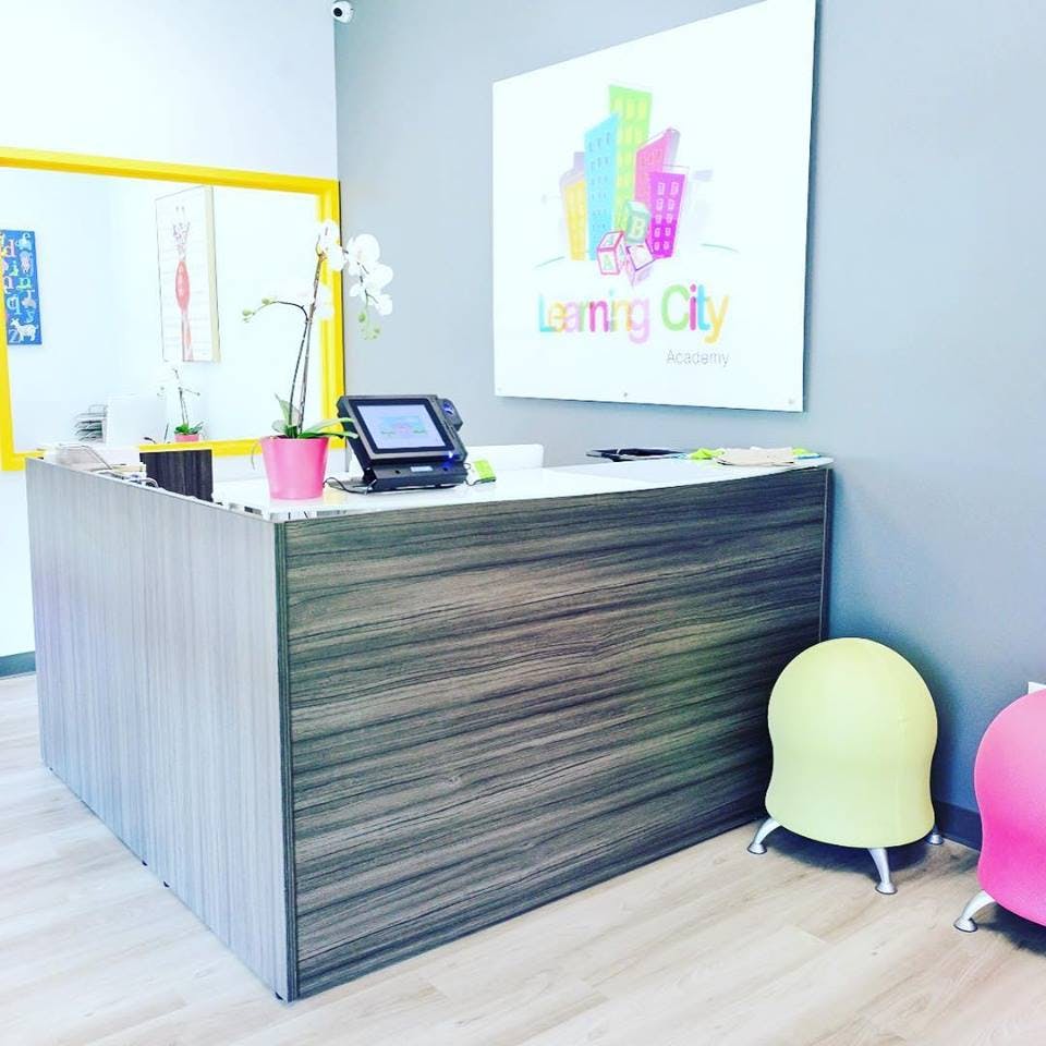 Reception desk with a plant and tablet, sign on wall says "Learning City"