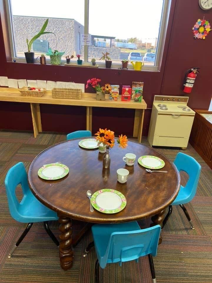 Round table set with plates and cups, surrounded by blue chairs