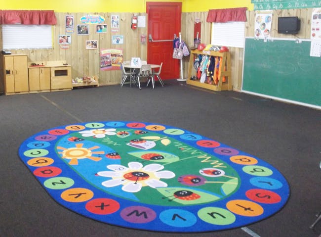 Classroom with a colorful oval rug featuring letters and flowers