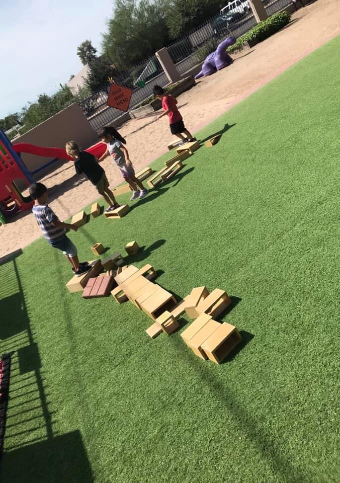 Children playing on wooden blocks on a grassy area