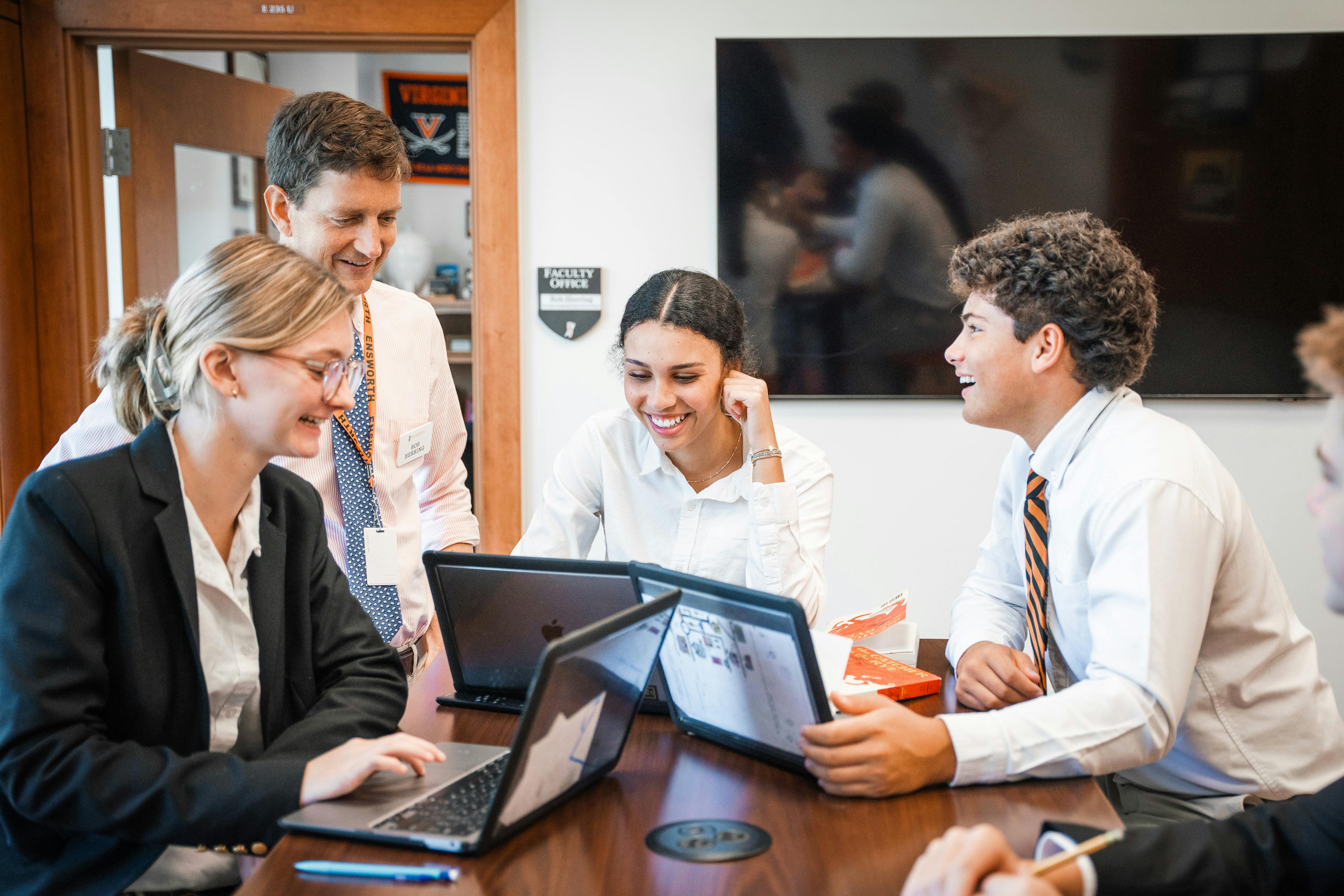 Group of people working together at a table with laptops in an office