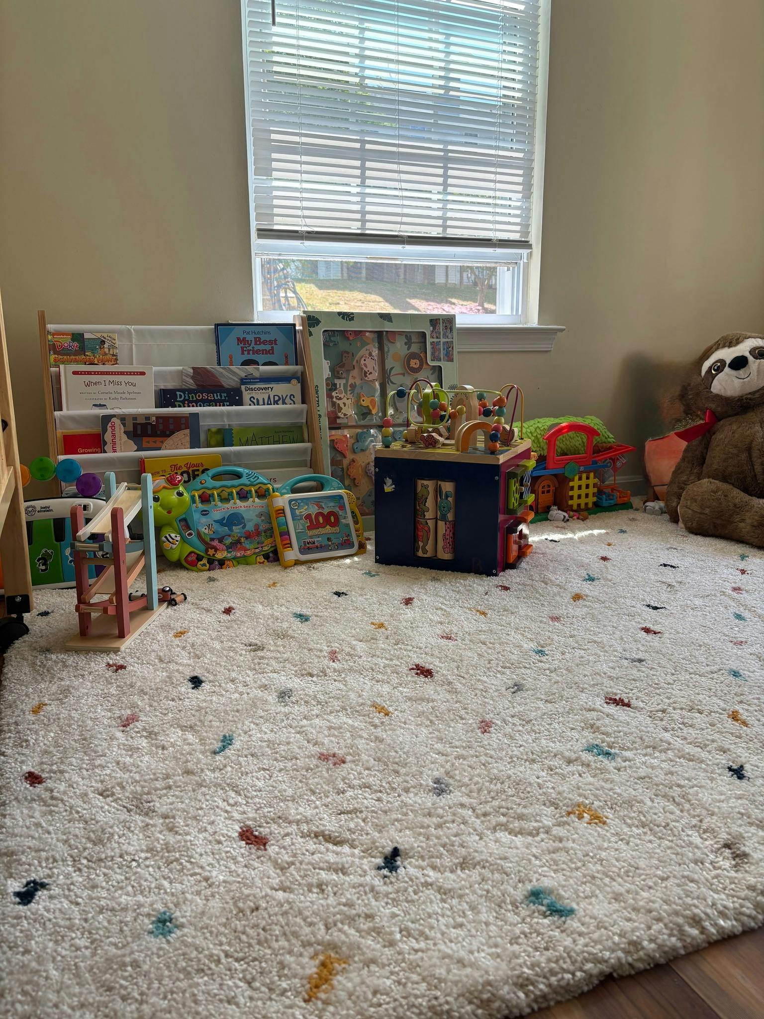 Playroom with toys, books, and a stuffed animal on a rug