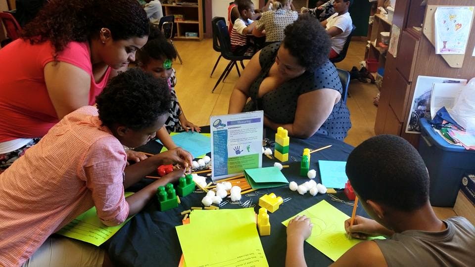 People and children at a table with craft supplies