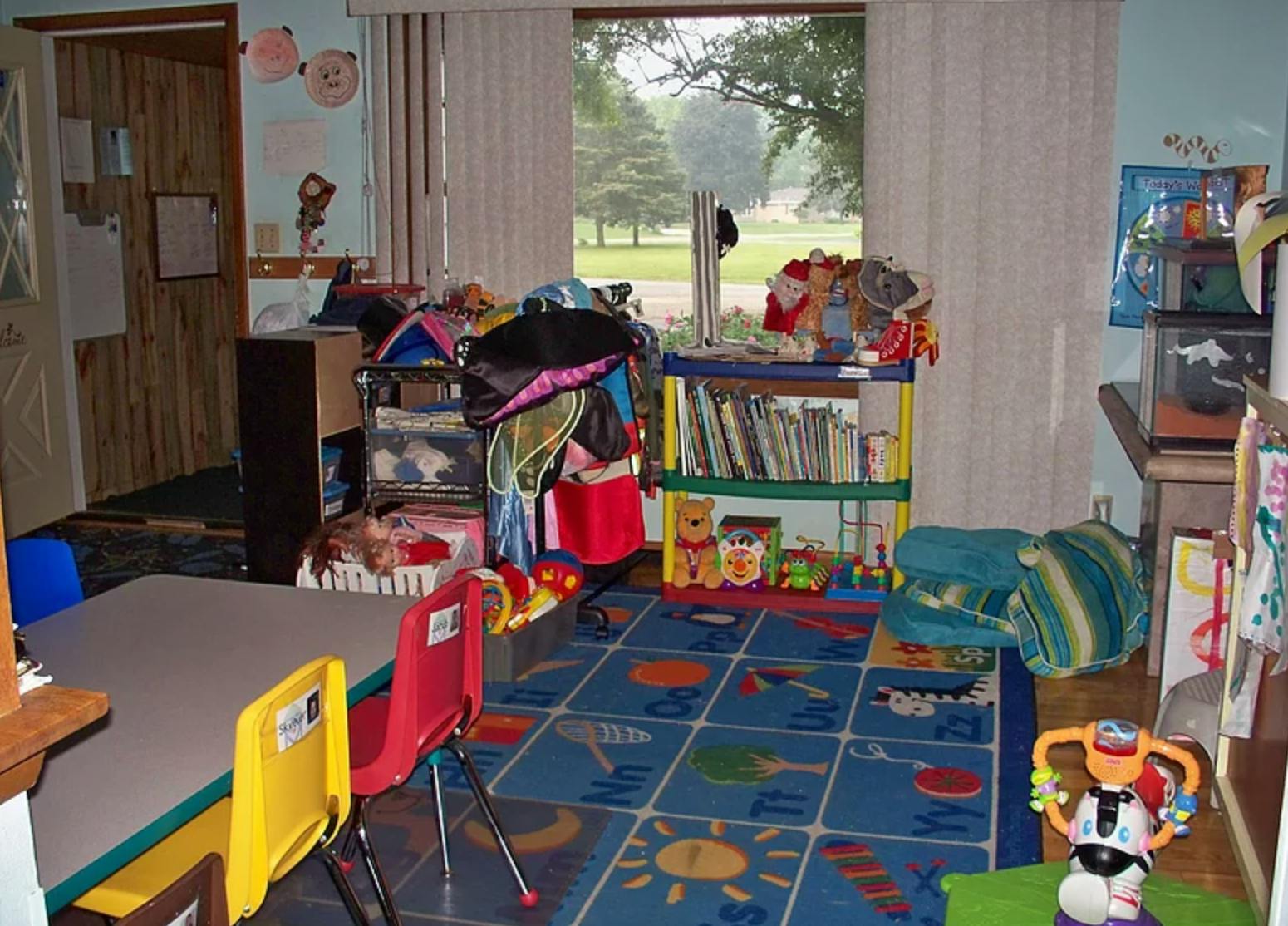 Messy room with a table and chairs, bookshelves, and a patterned rug