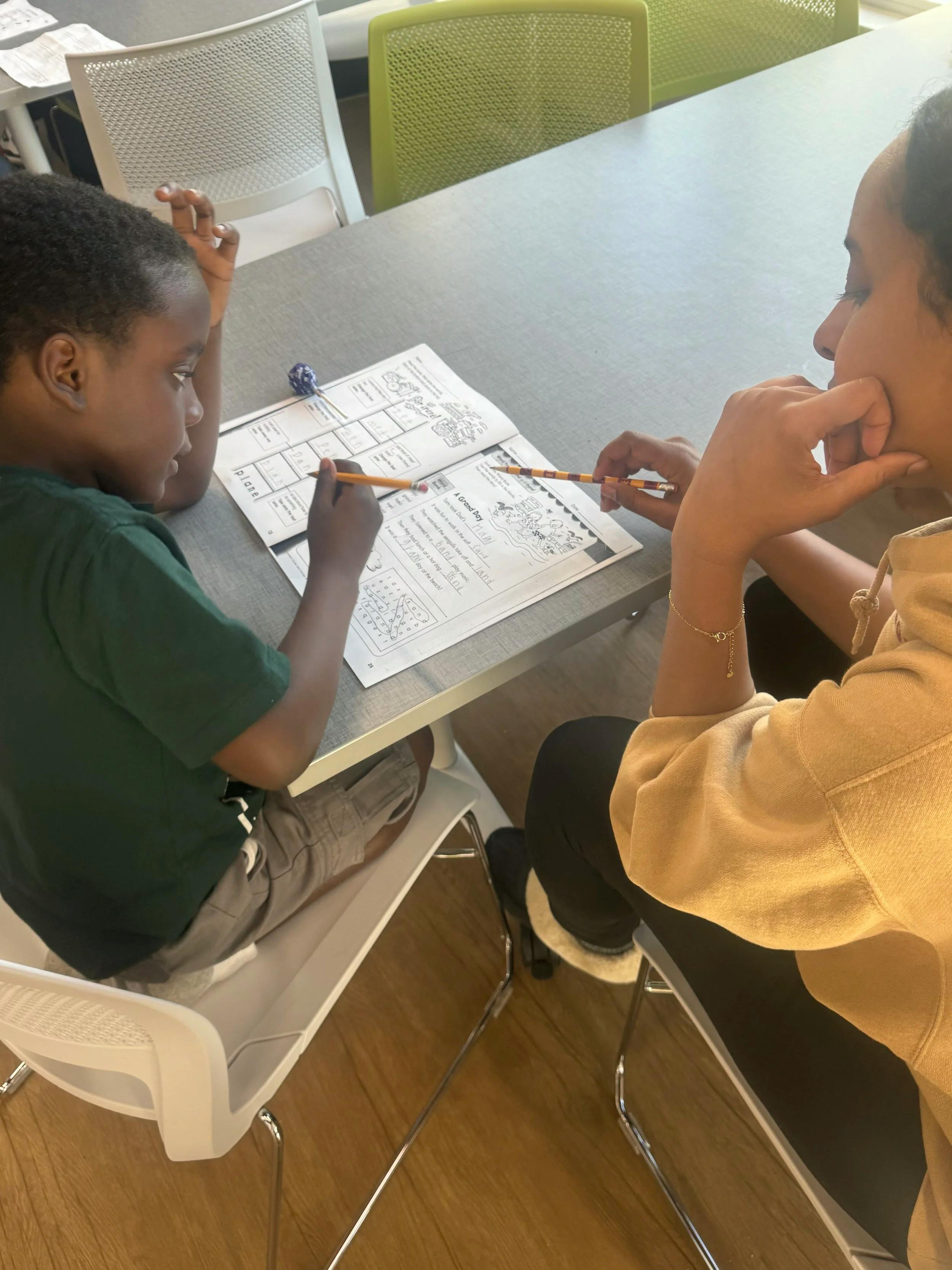 Adult and child doing schoolwork with pencils at a table