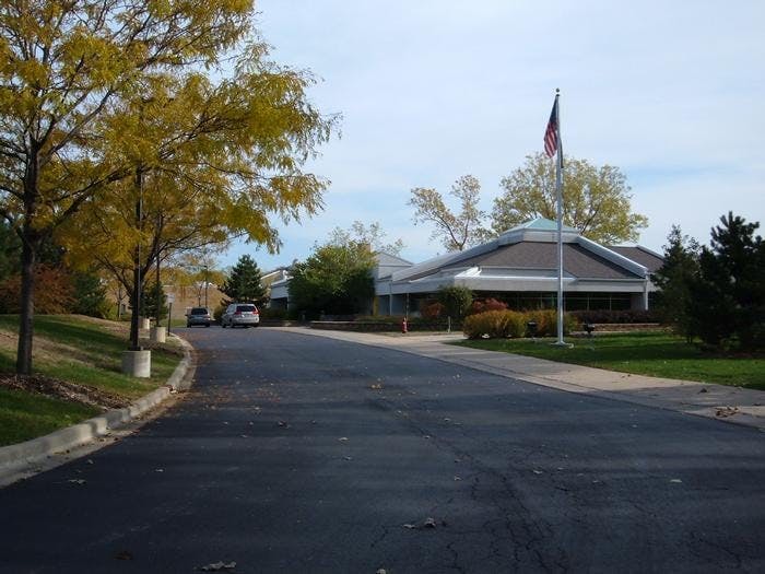 Road leading to a building with a flag pole in front