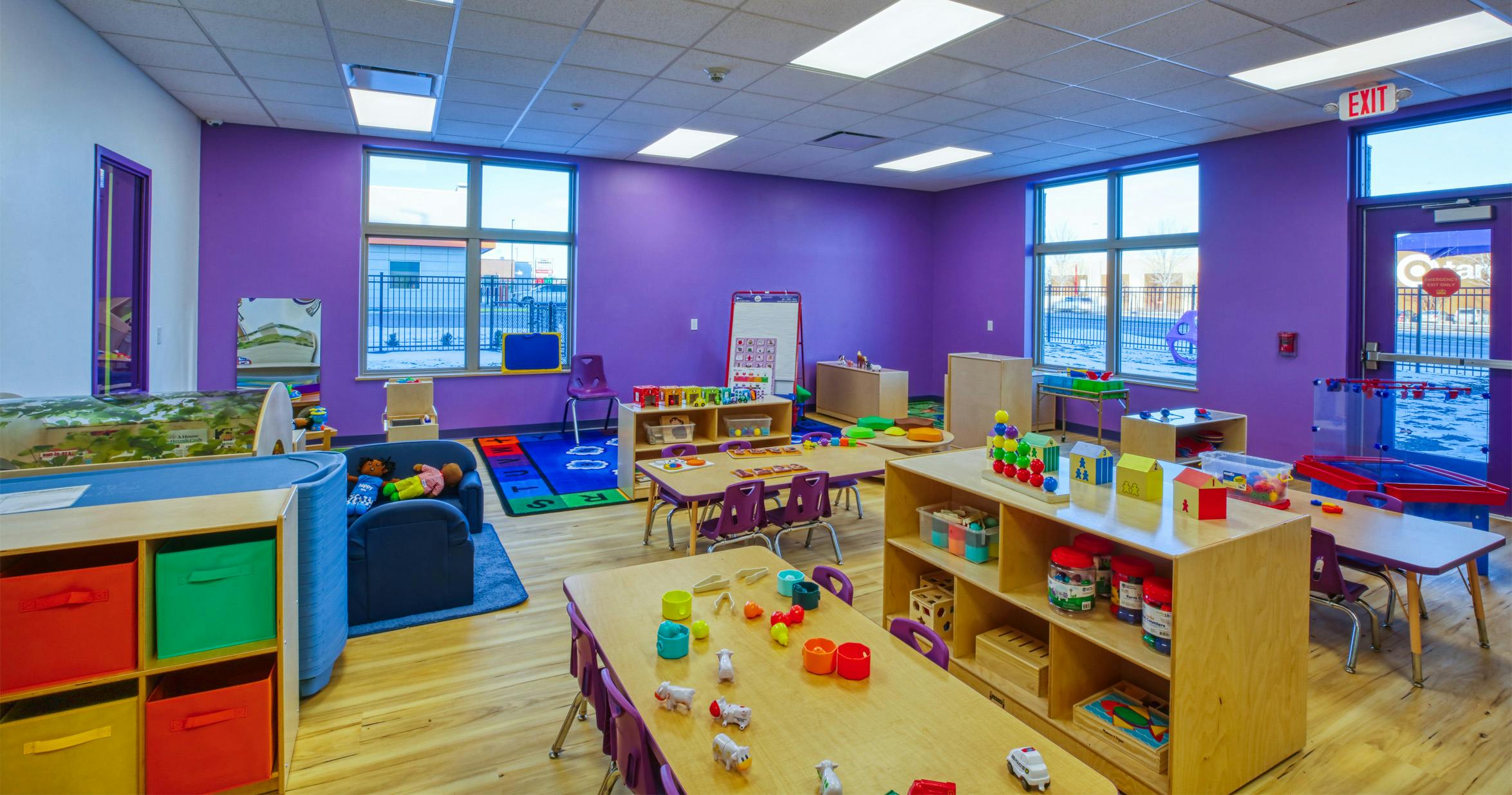 Classroom with purple walls, small tables, chairs, and toys