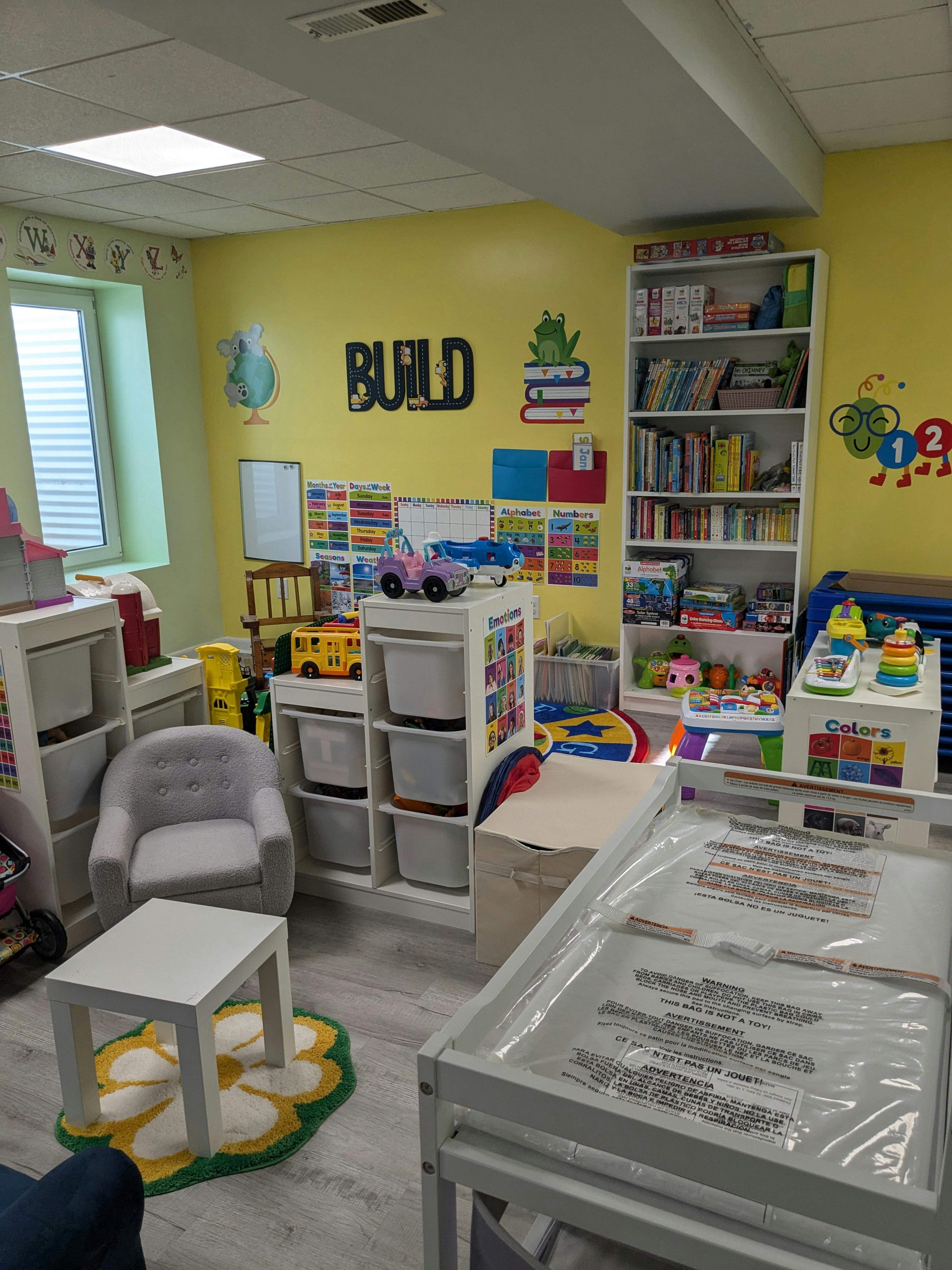 Children's playroom with toys, shelves, and a small table