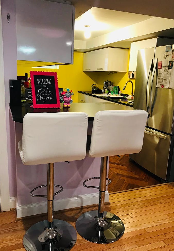 Two white bar stools at a kitchen counter with a sign that says "Welcome"