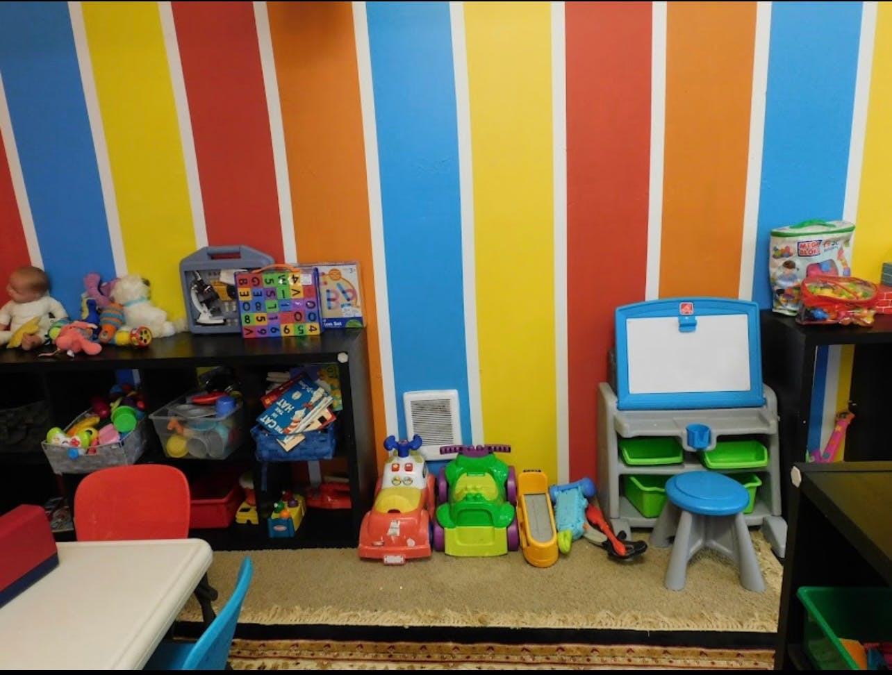 Playroom with colorful striped walls, toys, and a small table and chairs
