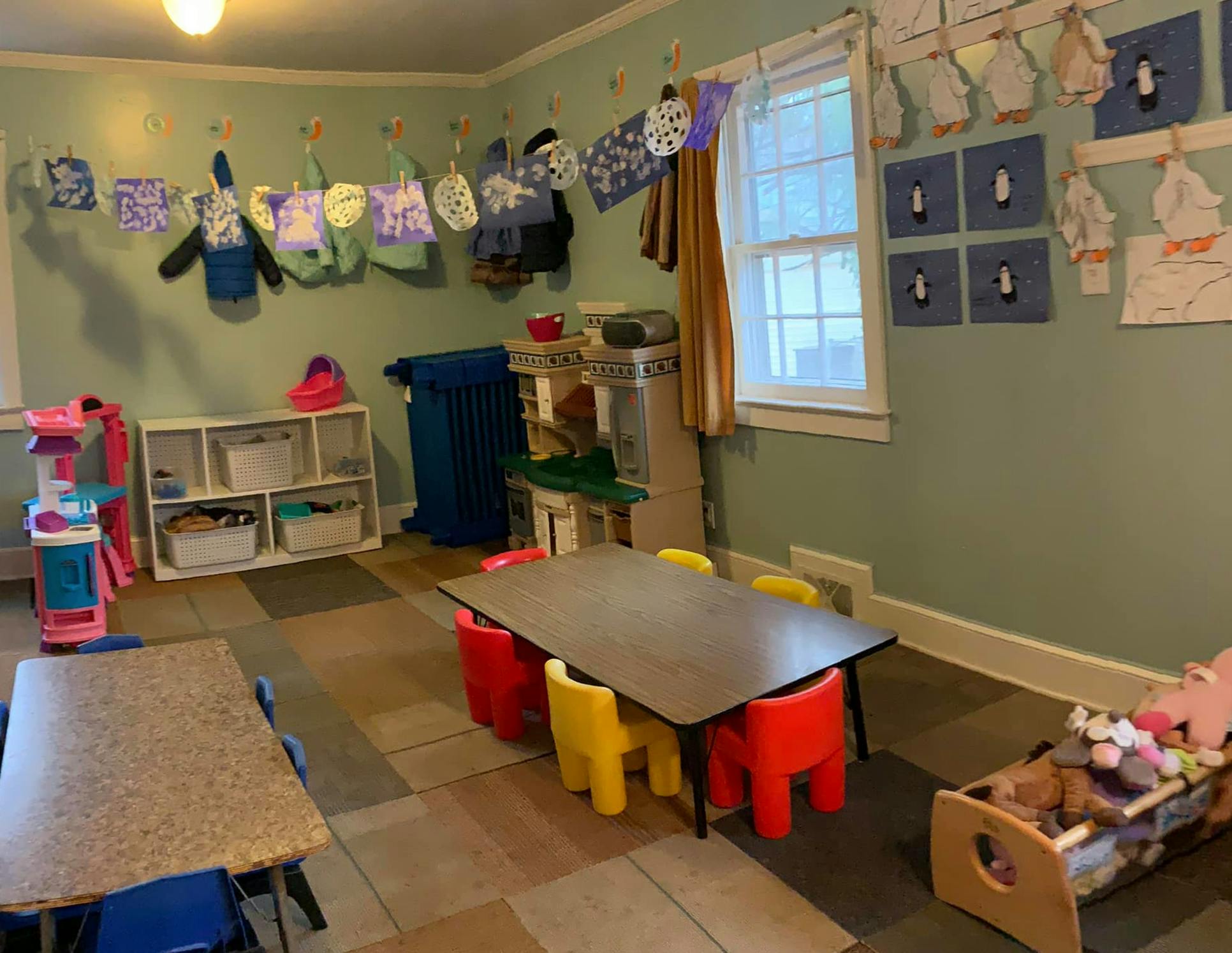 Classroom with small tables and chairs, shelves, and decorations on the wall