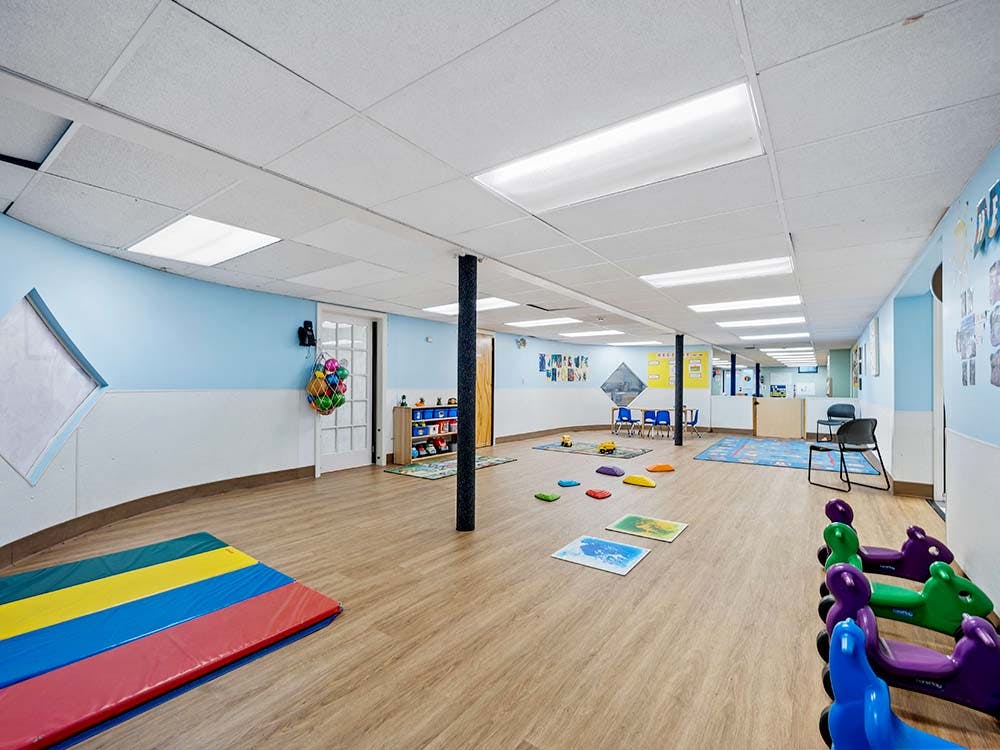 Children's playroom with floor mats, toys, and small tables