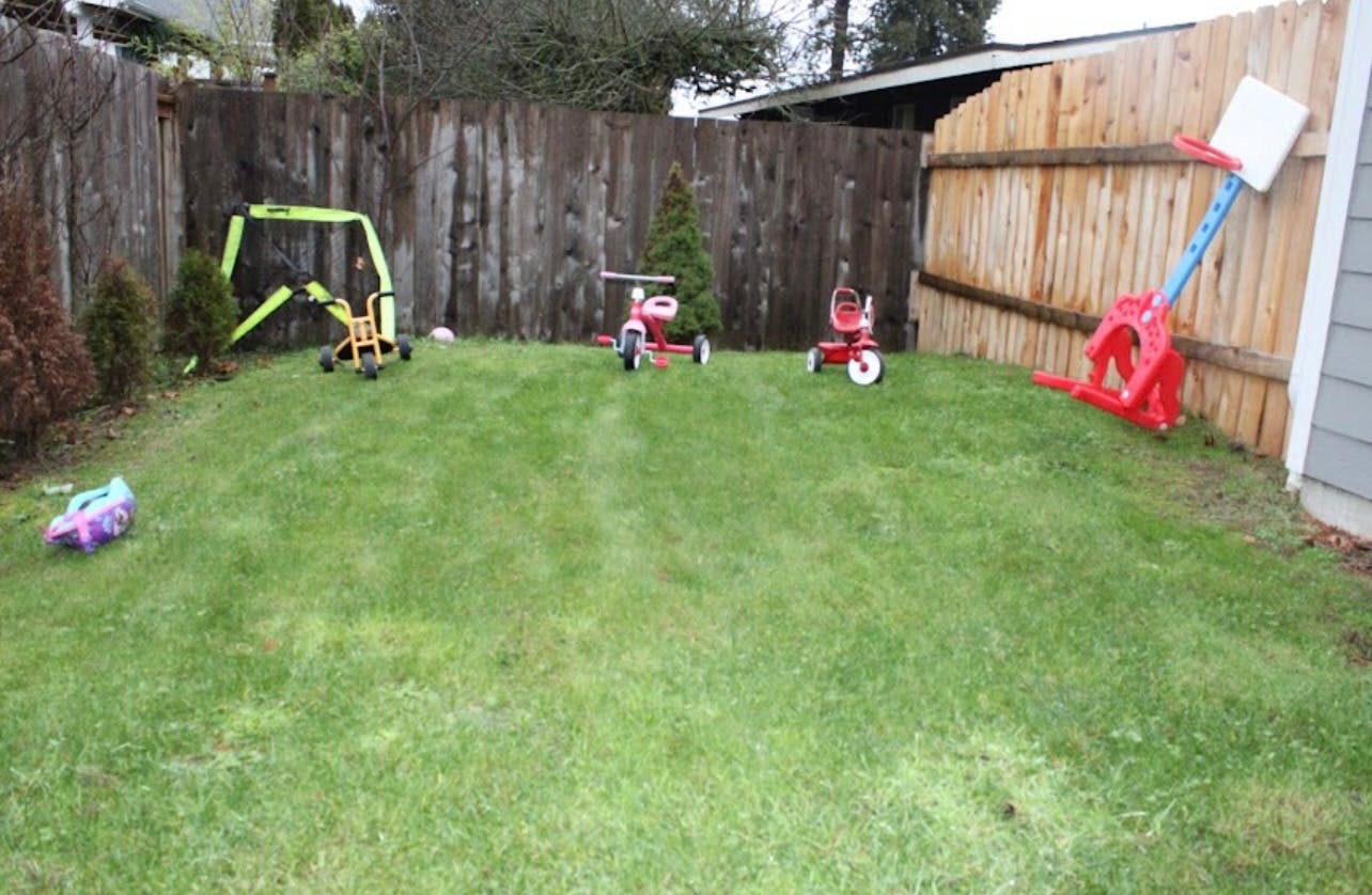 Backyard with children's toys including tricycles and a play excavator
