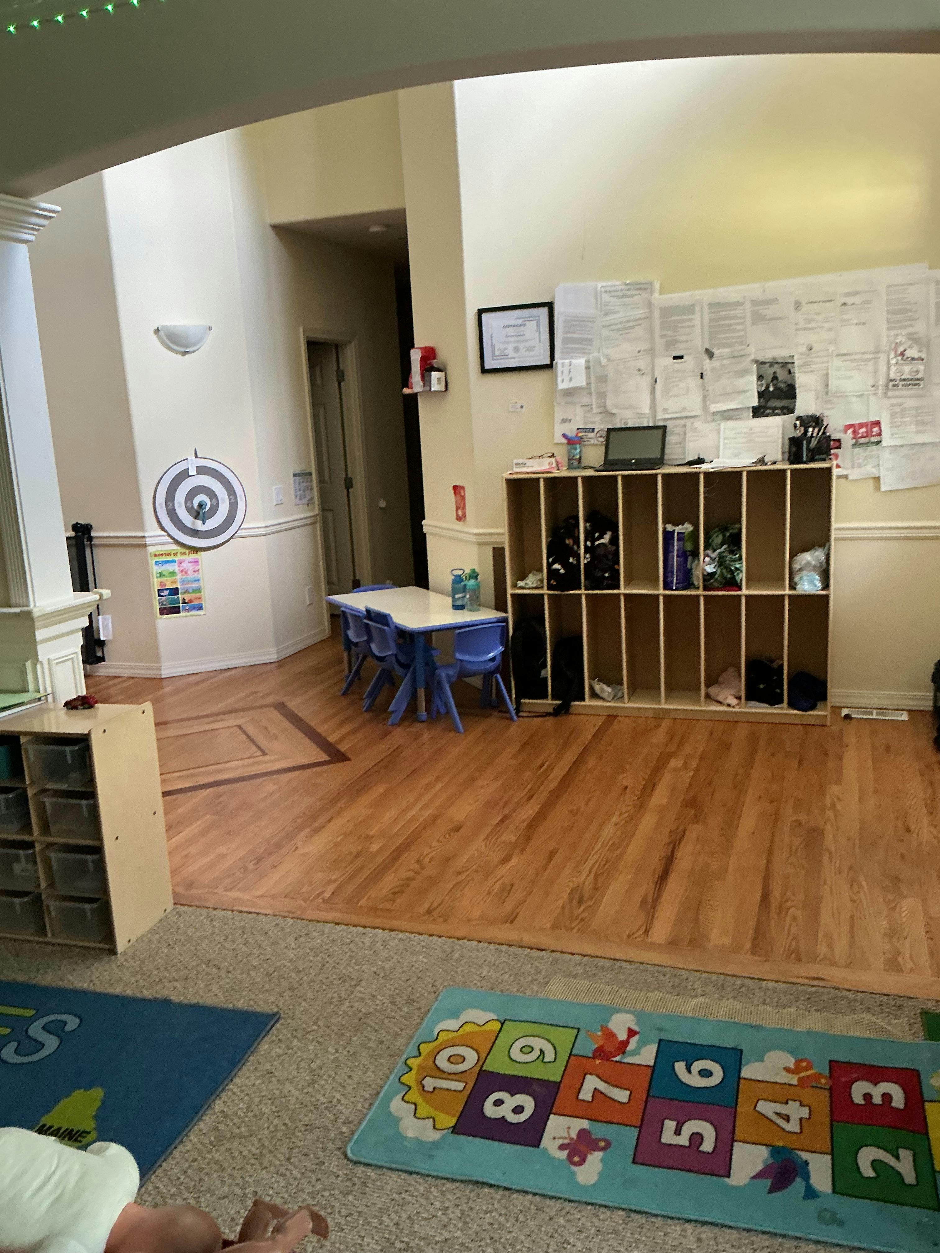Classroom interior with small tables chairs storage cubbies and a number rug
