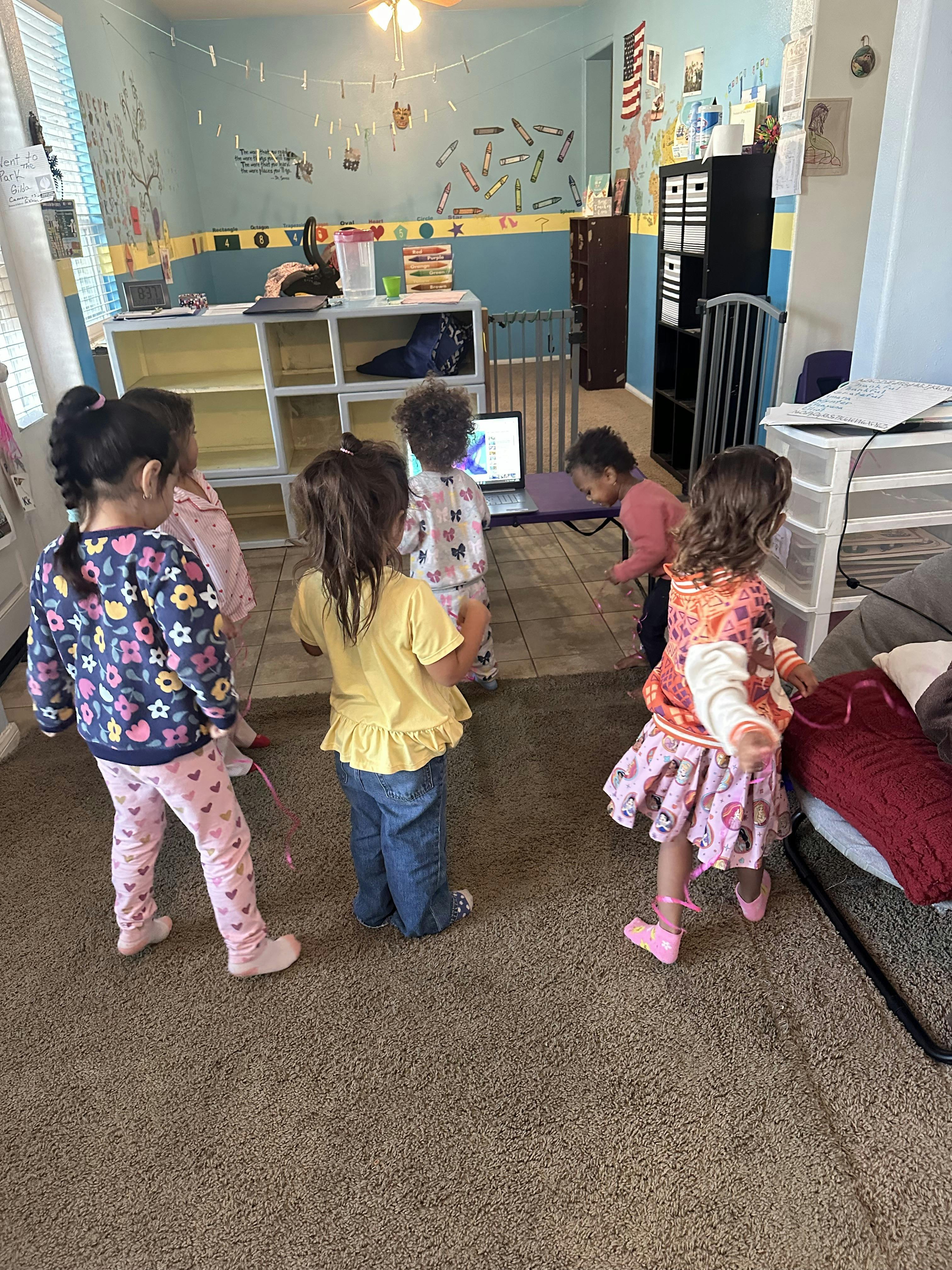 Five children playing in a room with a laptop
