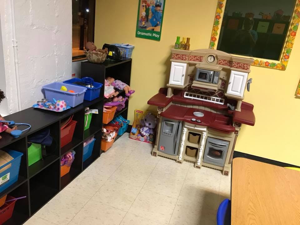 Play kitchen and storage shelves with colorful bins in a room