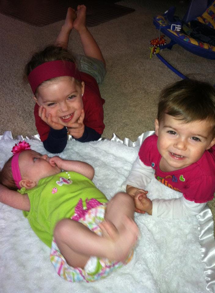 Two children and a baby on a white blanket