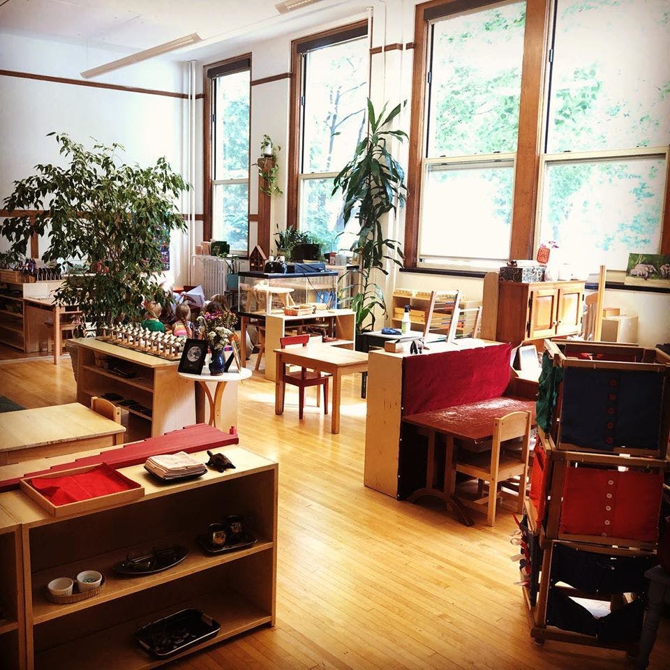 Classroom with small tables, chairs, and shelves with learning materials