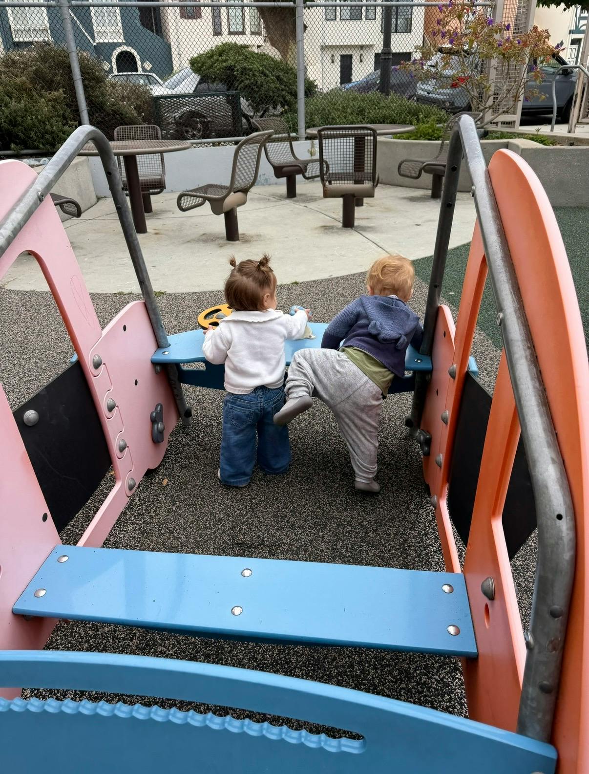 Two small children playing together on a playground structure